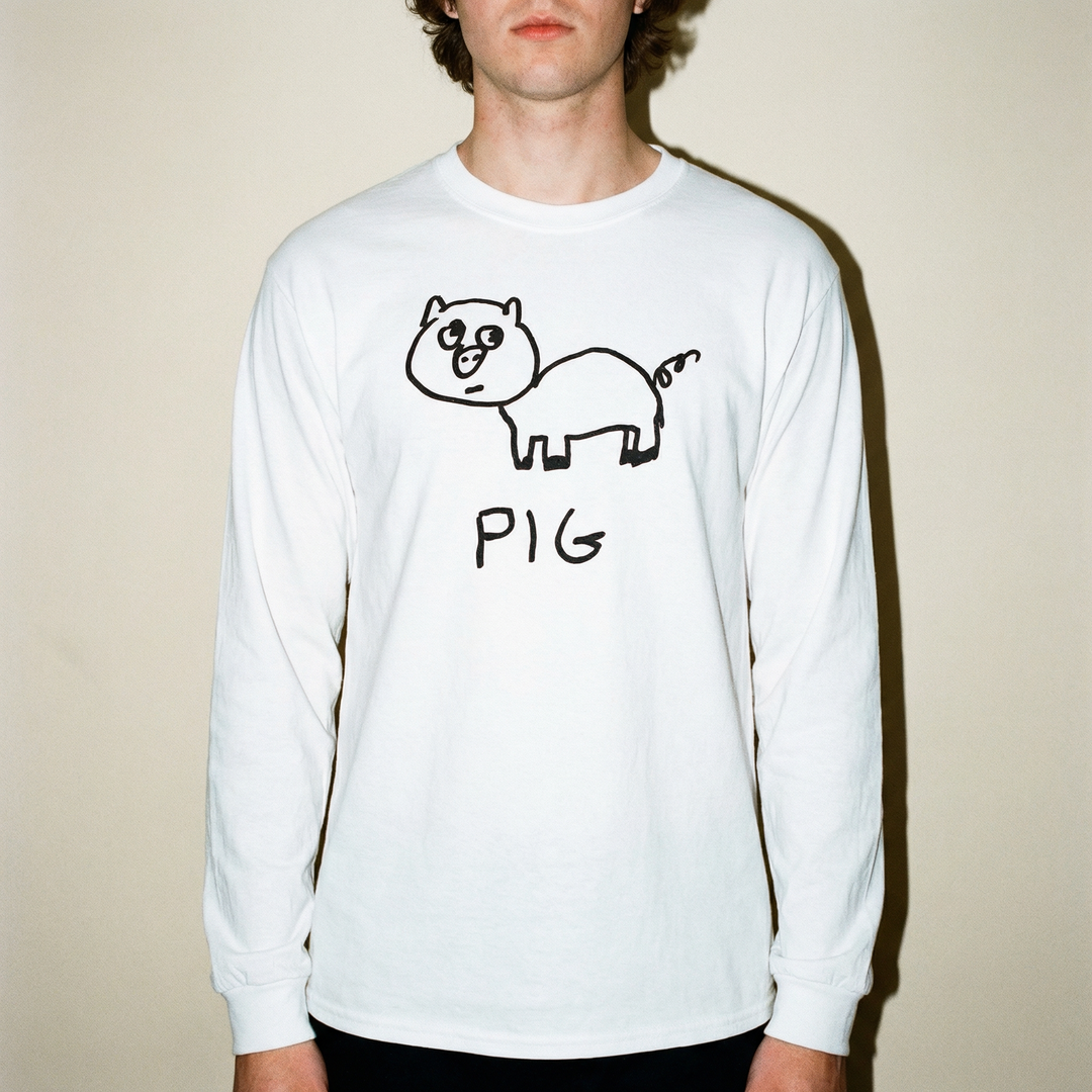 Model in a pig long sleeve tee photographed close-up in a bright minimal studio