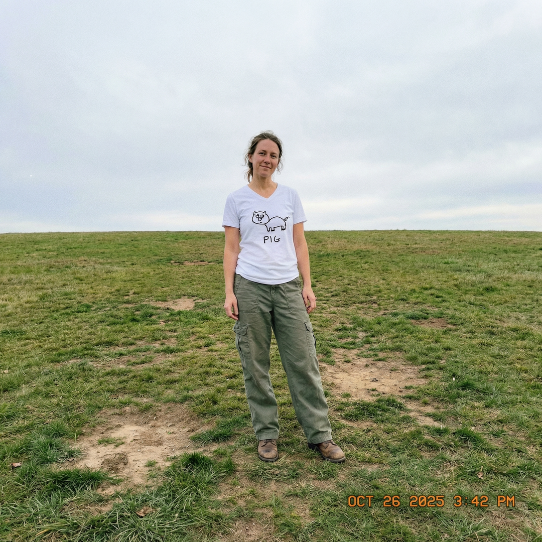 Model in pig v-neck tee in a lush green field, easy afternoon light