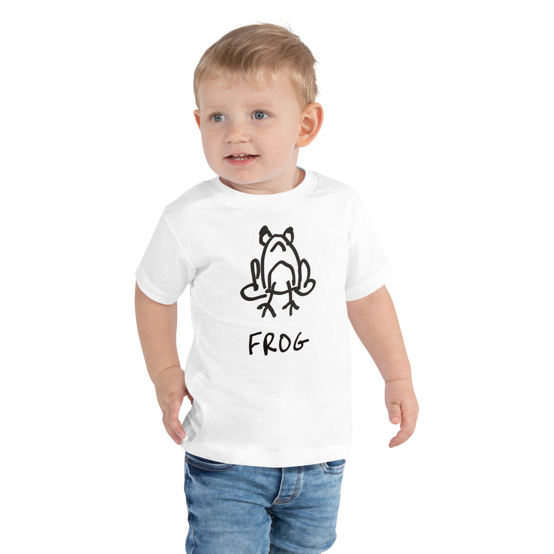 toddler wearing a white toddler t-shirt with a lo-fi hand-drawn frog graphic and "FROG" text on a white background. 