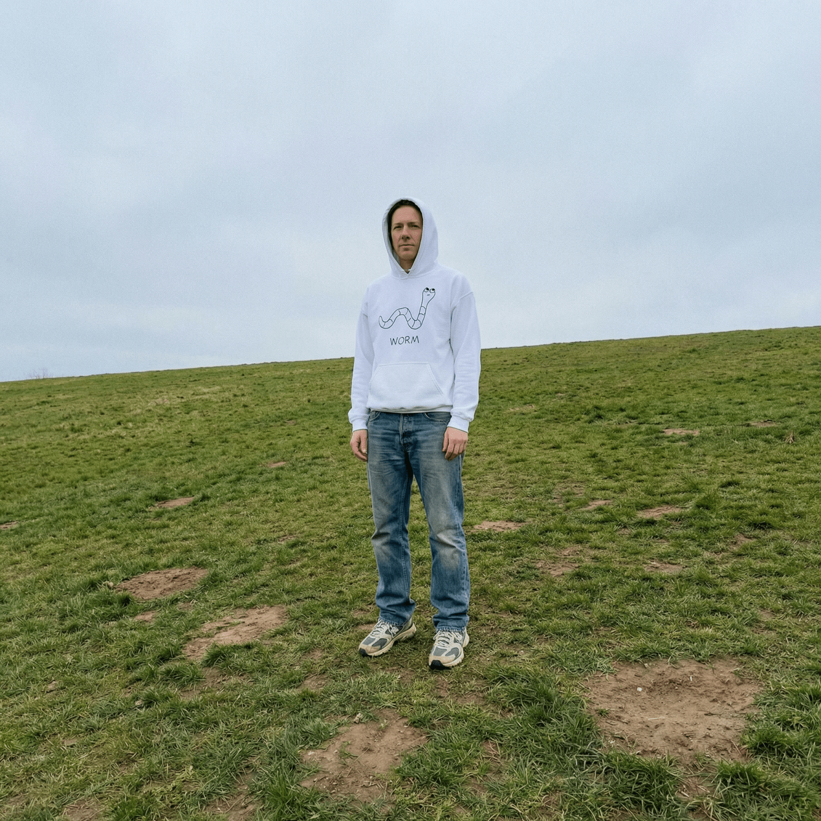 Man standing in an open grassy field wearing a lo-fi Worm Hoodie